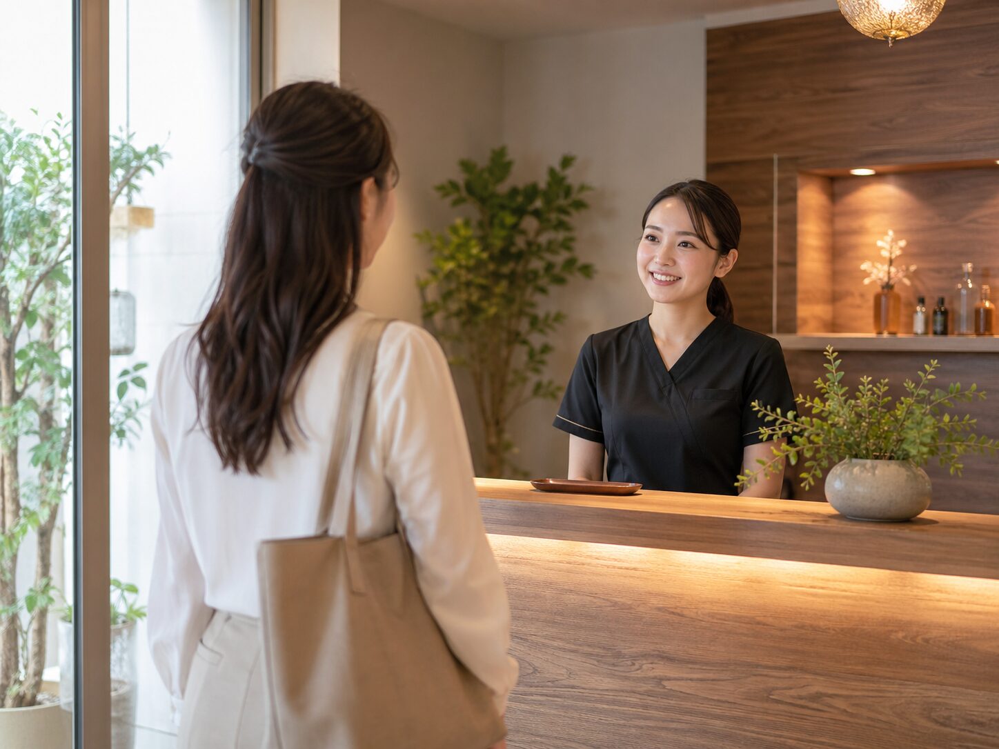 女性のお客様がサロンに来店し、受付スタッフが笑顔で迎えているイメージ画像